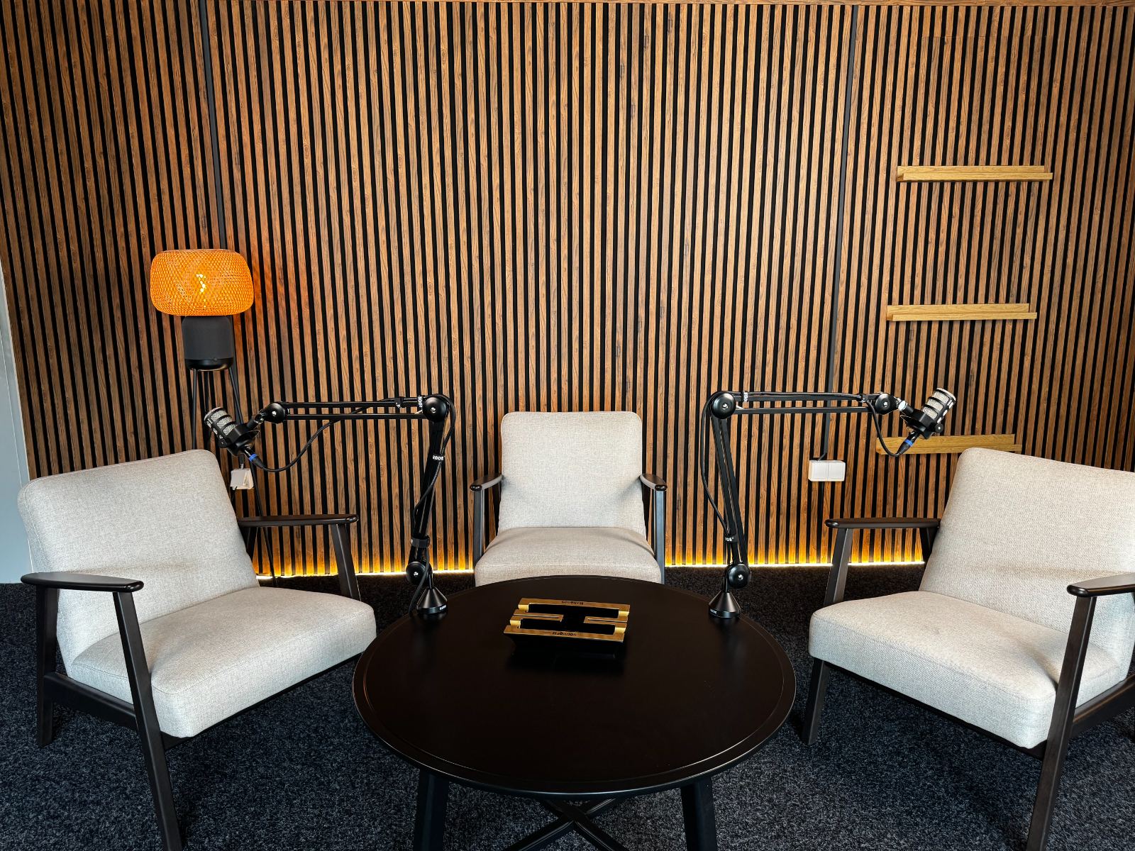Podcast studio u Beogradu — tri stolice, okrugli sto, RODE boom mikrofoni i drveni akustični panel
